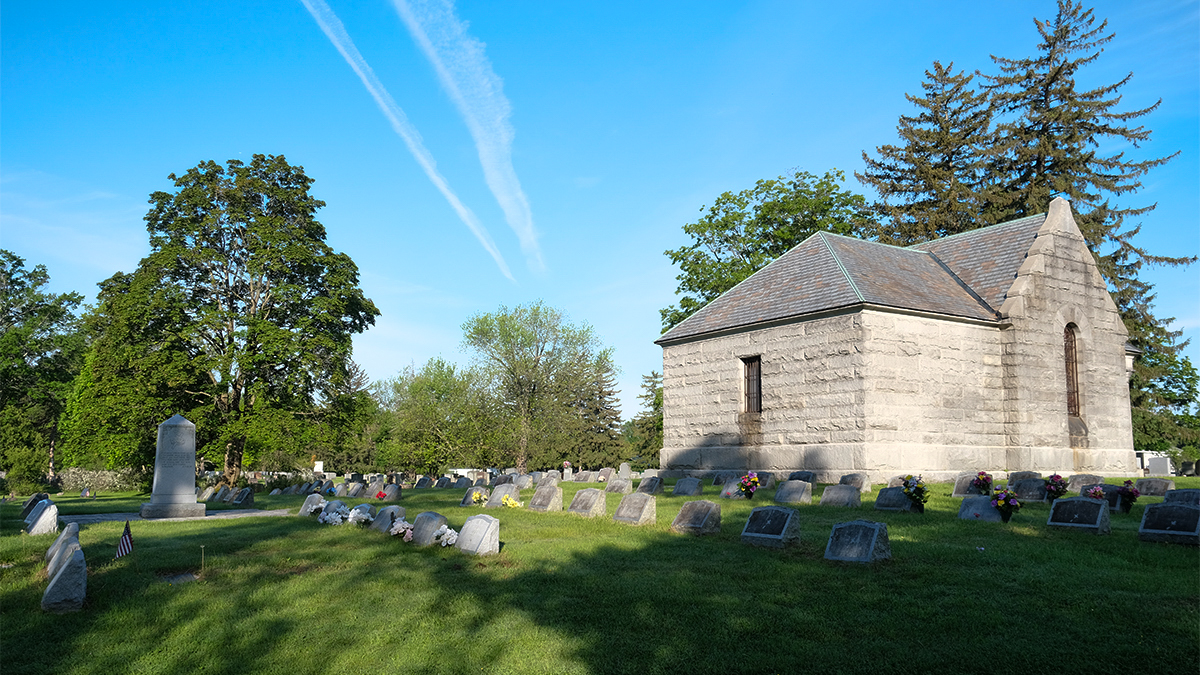 Grass, grave markers, and trees to the left; structure on the right
