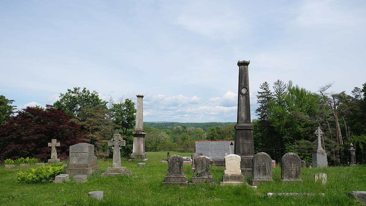 Grave markers in foreground, trees and blue sky in background