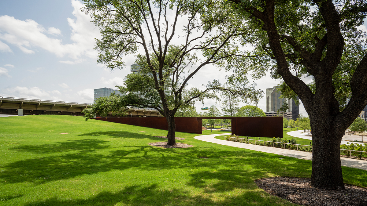 Sloping lawn with trees in foreground; metal passageway in background