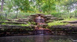 Stone waterfall and pond with trees around
