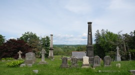 Grave markers in foreground, trees and blue sky in background
