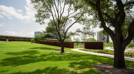 Sloping lawn with trees in foreground; metal passageway in background