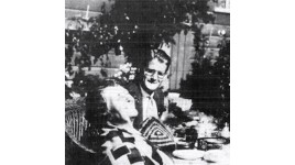 Man sits at outdoor table looking at woman