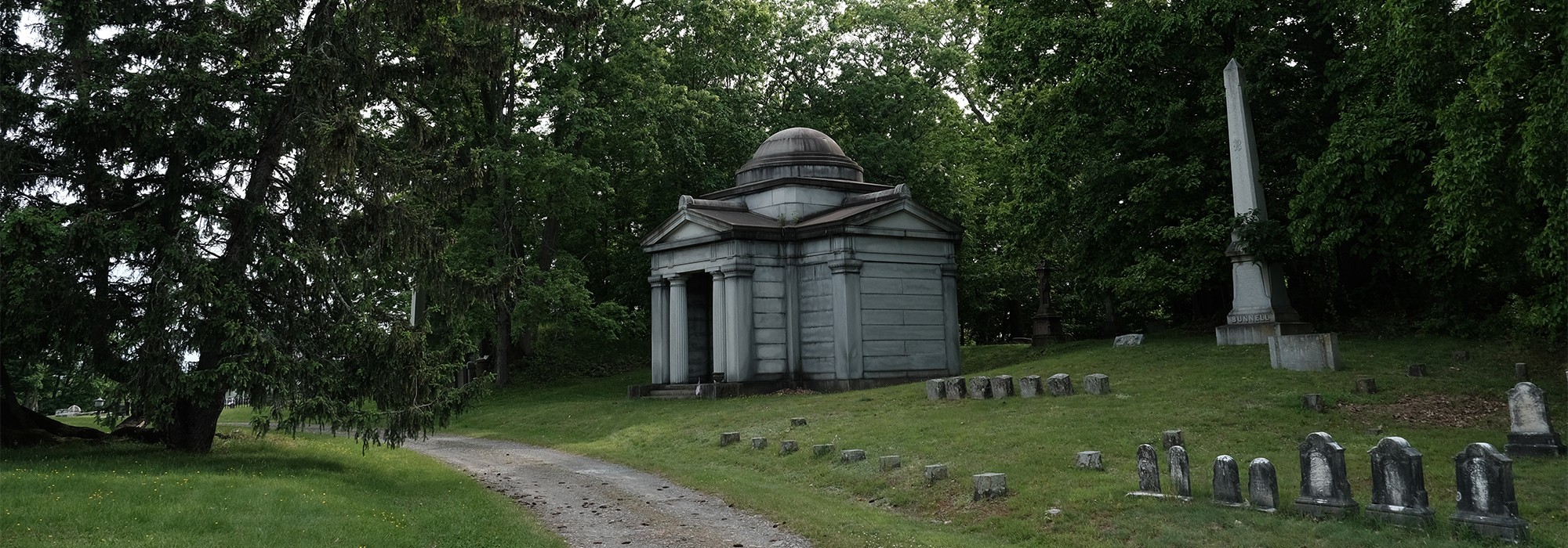 Path curves past mausoleum and smaller grave markers