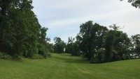 Rolling lawn with large, shady trees all around.