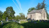 Grass, grave markers, and trees to the left; structure on the right