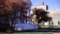 Building on the left iwth trees on either side; path and lawn on the right