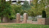 Brick entryway fronted by a lawn with trees in the background