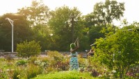 Woman in center dancing, surrounded by flowering plants and trees.