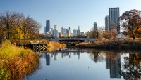 River with lush banks on either side; buildings in distance