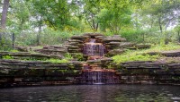 Stone waterfall and pond with trees around