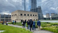 Groups of people walk through gardens; skyscrapers in background