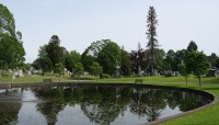 Body of water in the foreground, grave markers and trees surround