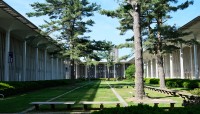 Open air courtyard with grass and trees, building with colonnade surrounds
