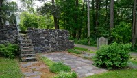 Stone wall and staircase enclosing small patio; path and trees in background