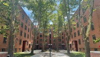 Brick buildings surrounding a paved courtyard with trees