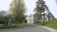 Driveway lined by lawn and trees leading to school