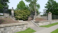 Stone staircase with sidewalk on the right and shrubs and trees to the left