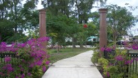 Two granite columns mark entrance to memorial; bougainvillea blooms on the gate