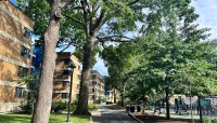 Building on the left; trees and sidewalk in center; playground on the right