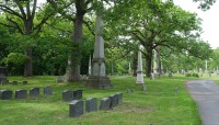 Grave markers in foreground, trees in background; road on right