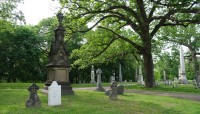 Grave markers on the left and in background; tree on the right