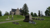 Path leads up a hill to stone structure in background; grave markers in foreground