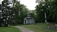 Path in center leads past mausoleum, smaller grave markers, and trees