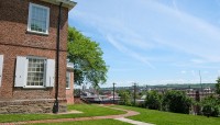 Red brick building on the left, pathways around it; city visible in the distance