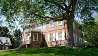 Red brick building in the center, shaded by tree on the right