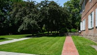 Red brick building on the right; lawn with walking path and trees on the left