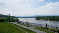 Pathway along the riverfront; lawn on the left; river and mountains on the right