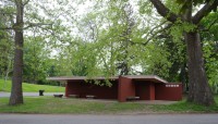 Low, brick building surrounded by trees