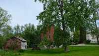 Row of buildings along sloping lawn; trees in foreground