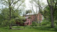 Two buildings in distance; lawn and grove of trees in foreground