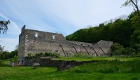 Crumbling stone structure; forest behind it