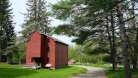 Red, wood building on the left; curving path and trees on the right