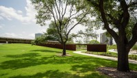 Sloping lawn with trees in foreground; metal passageway in background