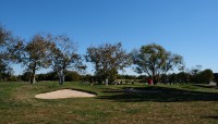 Sand traps in foreground; people golf in background