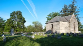 Grass, grave markers, and trees to the left; structure on the right