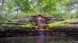 Stone waterfall and pond with trees around
