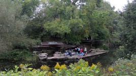 View of the pavilion from above; people gather near the water