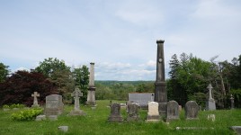 Grave markers in foreground, trees and blue sky in background