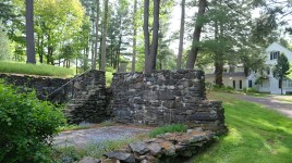 Stone wall and staircase enclosing small patio; house and trees in background