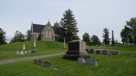 Path leads up a hill to stone structure in background; grave markers in foreground
