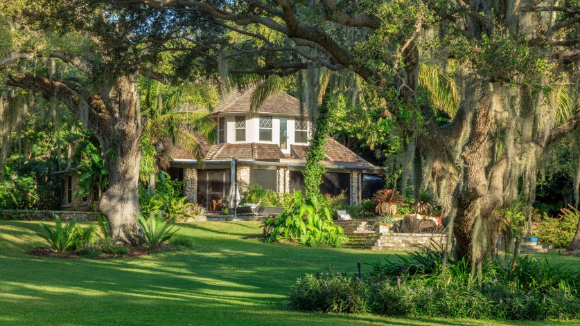House surrounded by grass and trees. 